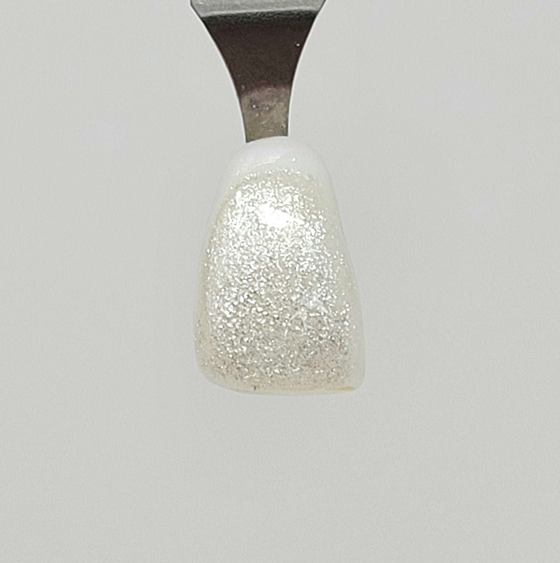Fine White Sparkle Temporary Tattooth Colorant on a demo tooth.  These colorants can be applied to teeth to temporarily alter their color or iridescence.